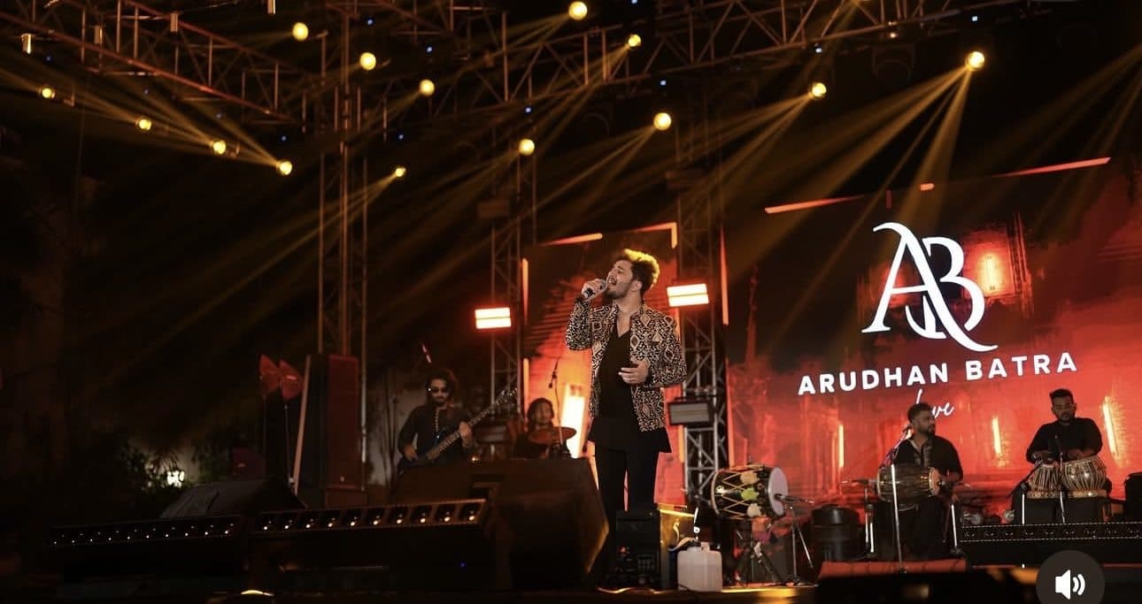 Arudhan Batra performing live on stage under amber light